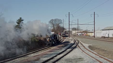 an aerial view of a steam locomotive backing up to connect to a passenger train