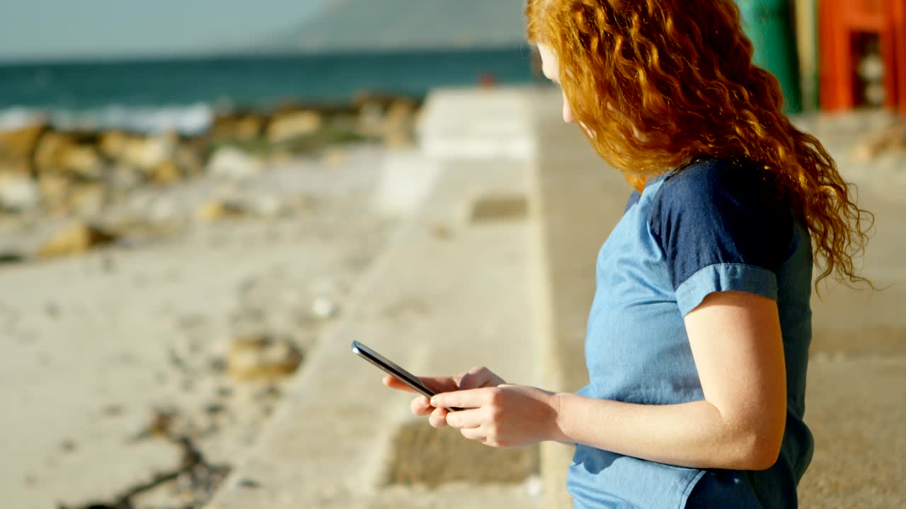 mujer tomando una foto con un teléfono móvil en la playa 4k