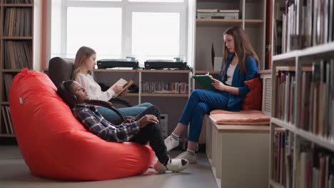 students learn material with tutor in library. woman conducts tests comparing reading book and listening to audiobook in college. studying methods