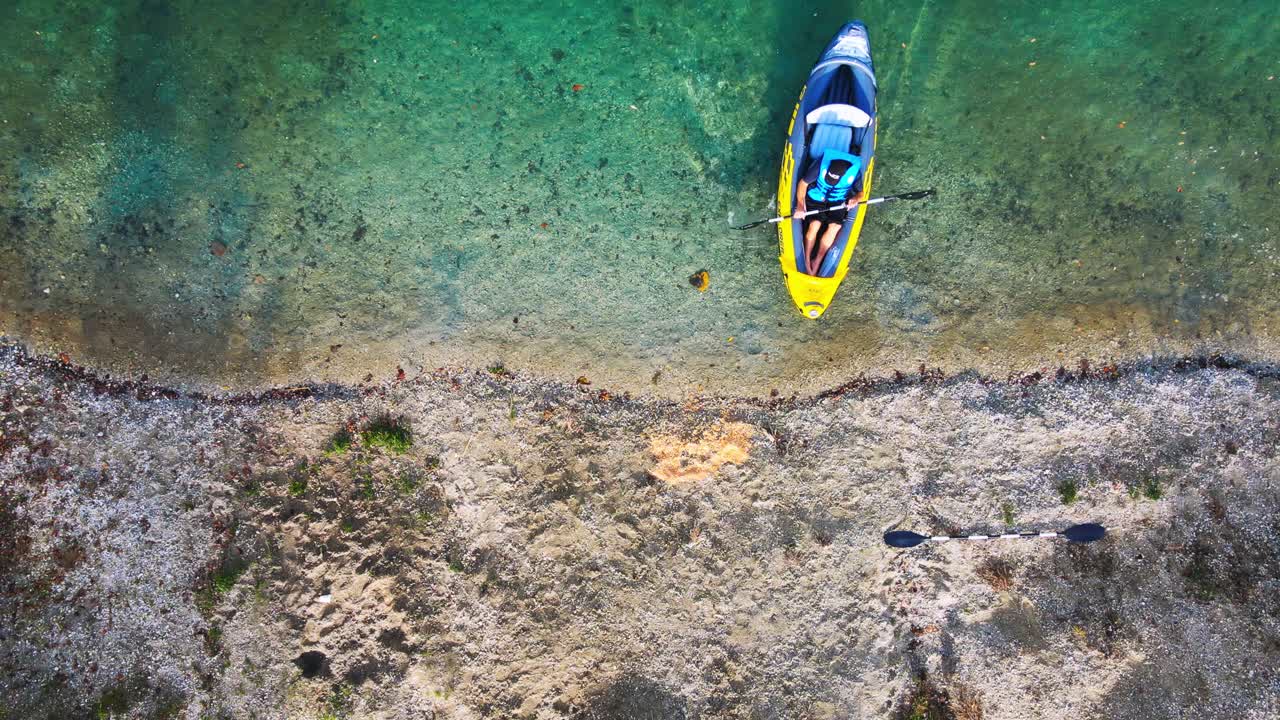 Stunning aerial 4K drone footage of a kayaker approaching the lake's banks and disembarking