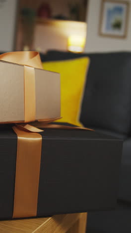 vertical video of pile of presents in gift wrapped boxes decorated with ribbon on table in lounge