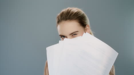 playful business woman holding paper documents in studio. female professional