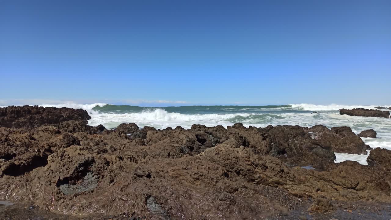 Un'inquadratura dal basso del mare agitato che si infrange contro gli scogli