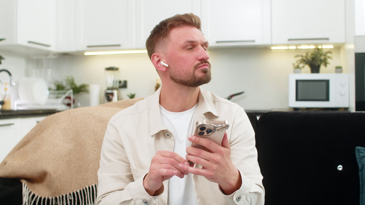 Young man studies online course on smartphone uses headphones listens lecture and sets weekly goal