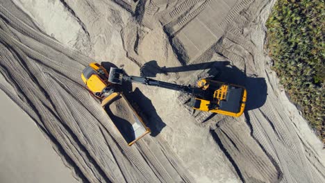 4k aerial overhead shot of excavators digging in the sand and working on the beach