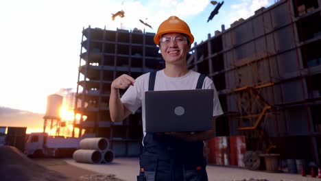 un trabajador asiático señala una computadora portátil en su mano en un sitio de construcción