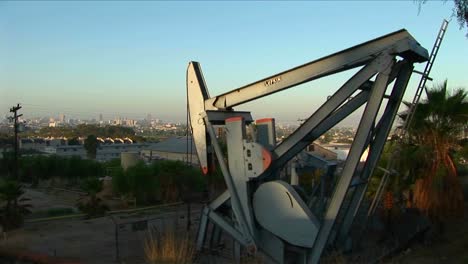 Un-Pozo-De-Petróleo-Bombea-Petróleo-Con-Un-Extenso-Paisaje-Suburbano-Detrás