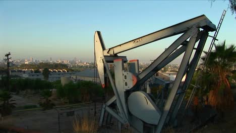 un pozo de petróleo bombea petróleo con un extenso paisaje suburbano detrás
