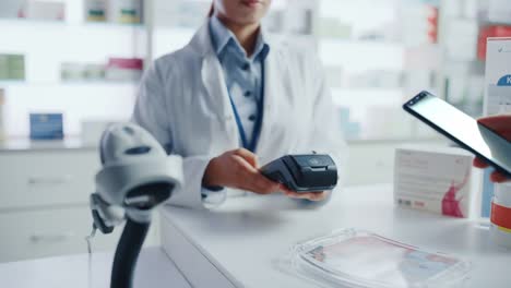 pharmacy drugstore checkout cashier counter: pharmacist and a customer using nfc smartphone with contactless payment terminal to buy prescription medicine, health care goods. hand focus closeup
