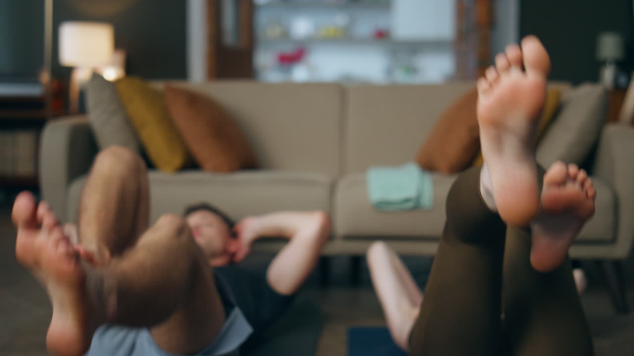 Nærbillede af ben, der spinner under fitnesstræning i lejligheden. Familie træner sammen.