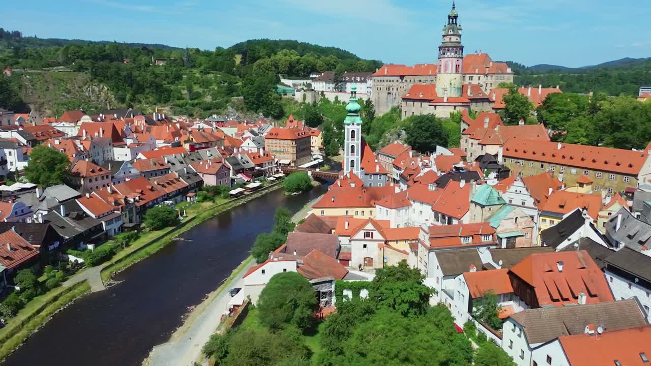 A slow flying down shot over a historic city centre. There are a bunch of old buildings and a castle in the middle. It's a sunny day with some clouds