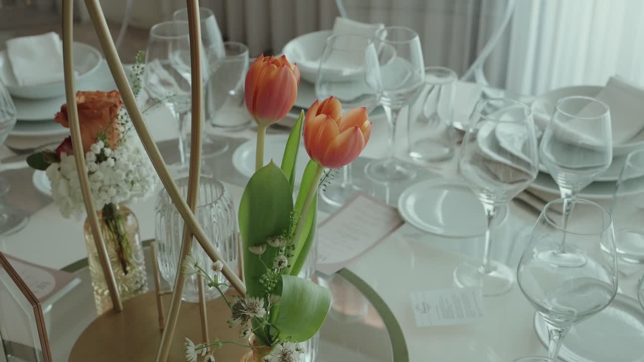 Nærbilde av bryllupsborddekorasjon med tulipaner, tallerkener og glass
