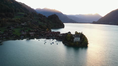 Amplia-Toma-Aérea-Giratoria-Cinematográfica-Del-Castillo-De-Iseltwald-En-El-Lago-Brienz-En-Suiza-Hacia-El-Sol