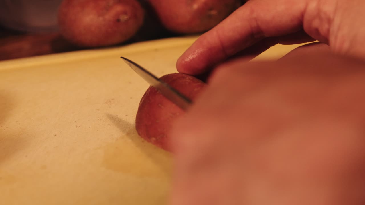 Chef Cutting Whole Red Potato into Wedges