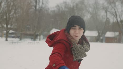 caucasian lesbian woman throws snowball towards the camera on a cold winter day - snowfall - handheld tilt-up shot