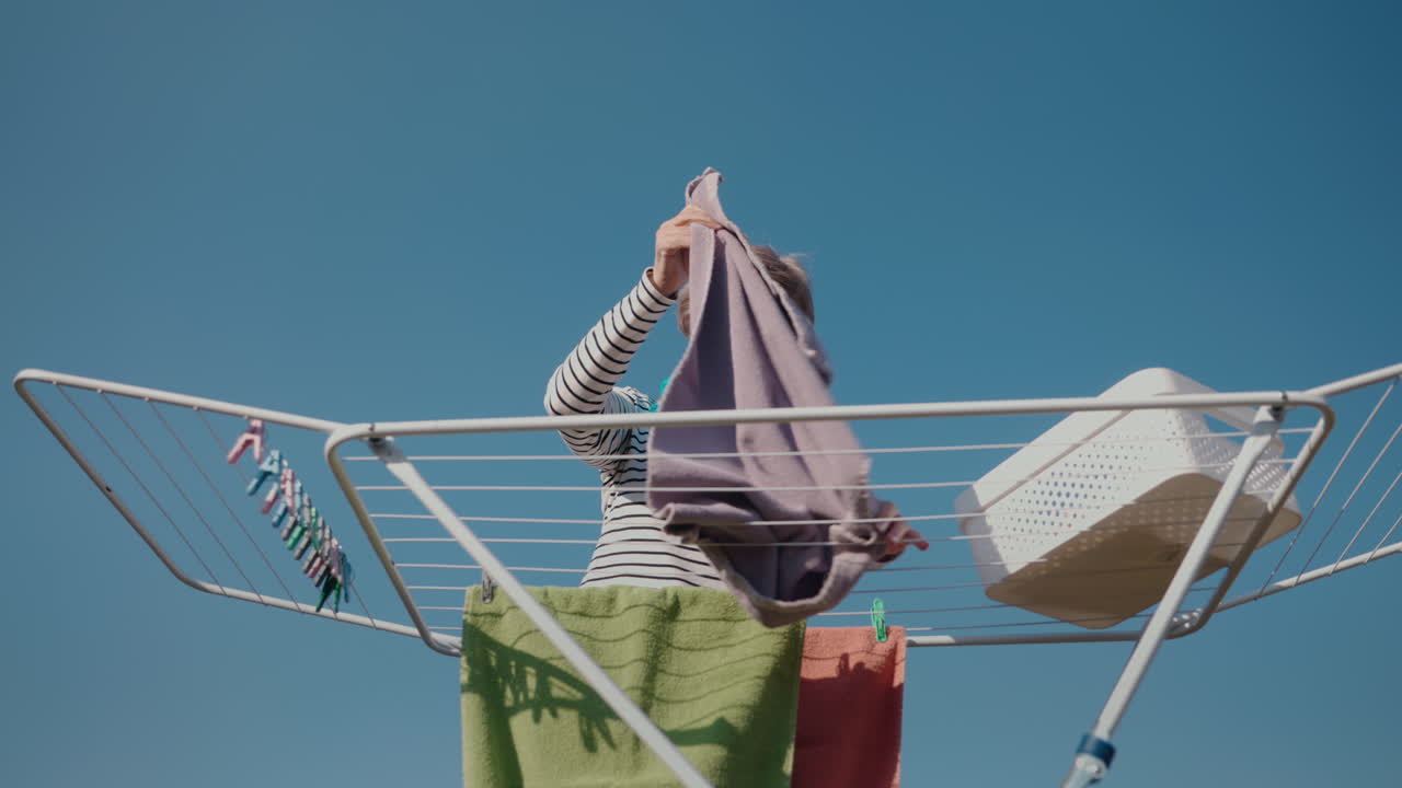 여자 가 옷줄 에 옷 을 매달고 있다