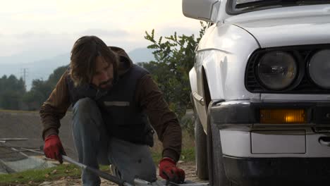 Mechanic-man-lowers-car-by-removing-floor-jack,-Slow-Motion