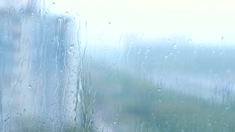 las gotas de lluvia fluyen por el vidrio en primer plano.