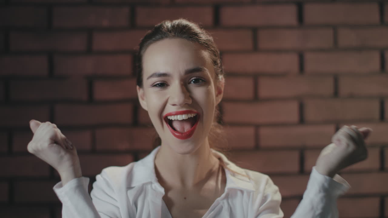 mujer saliendo riendo y regocijándose buenas noticias en el fondo de la pared de ladrillo