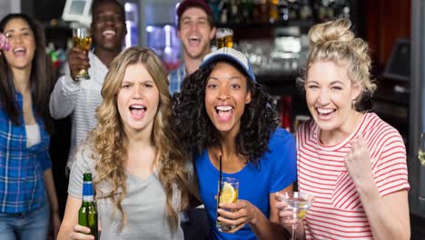 happy diverse female and male sport fans watching game at bar, cheering and drinking