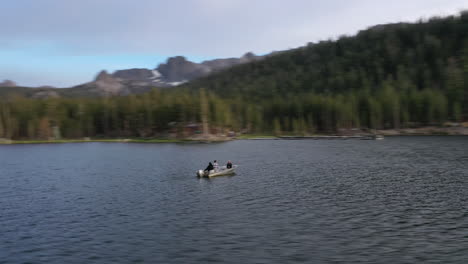 vista aérea girando alrededor de un bote en un lago de montaña rodeado por un bosque de pinos en lagos gigantescos, ca