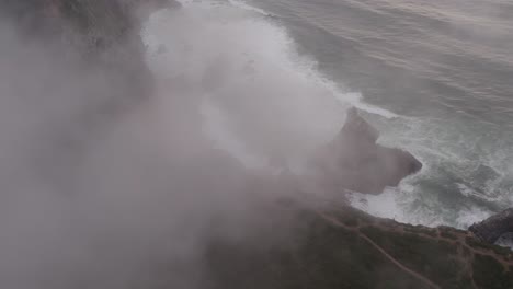 low clouds at praia da ursa portugal during a cloudy sunset, aerial