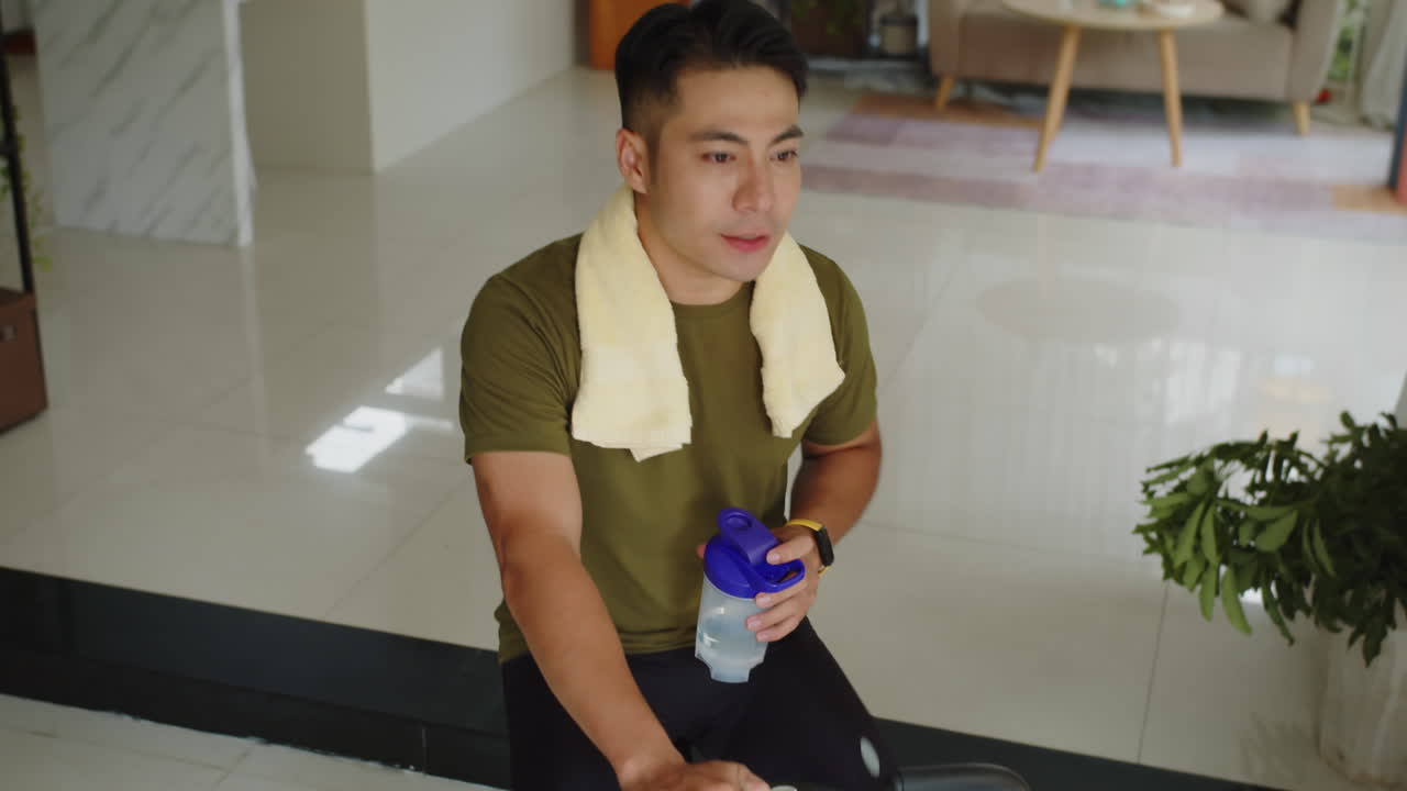 Man Drinking Water when Cycling on Fitness Bike at Home