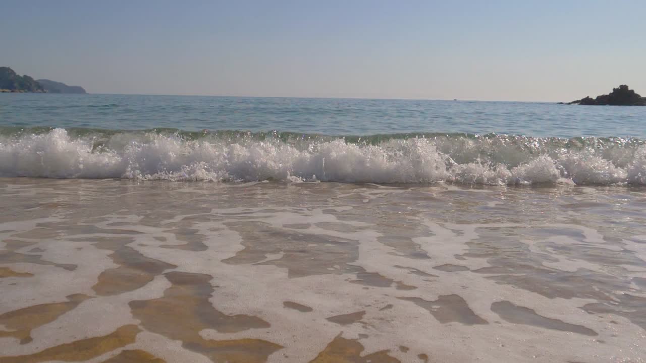 Bellissima costa mediterranea, con onde di acqua limpida che si infrangono dolcemente sulla riva.