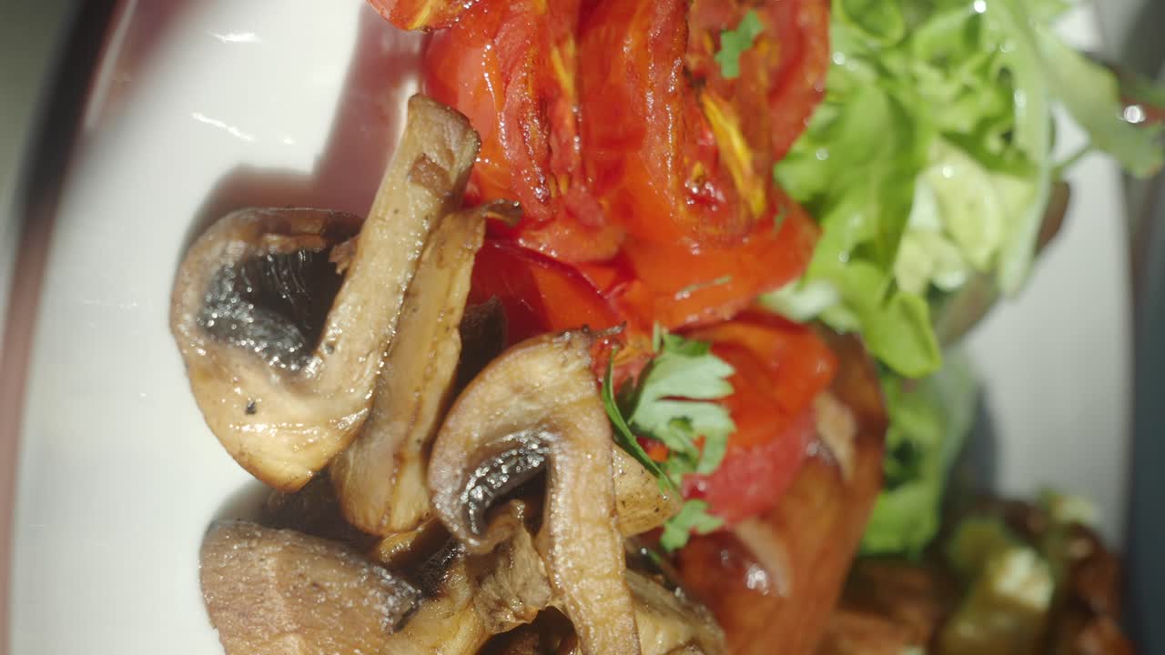 Close-up of a plate with sautéed mushrooms, tomatoes, and greens