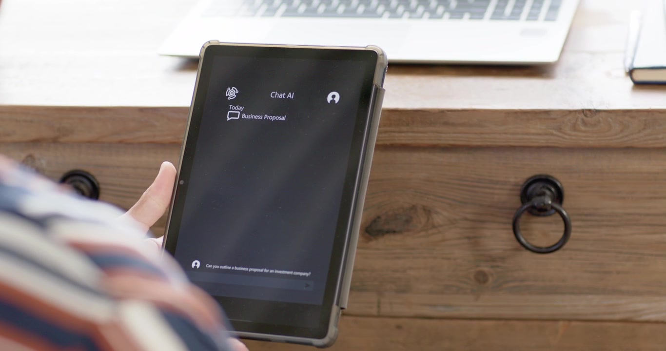 Right thumb is starting scroll, user is adjusting tablet and reading replies at desk with laptop