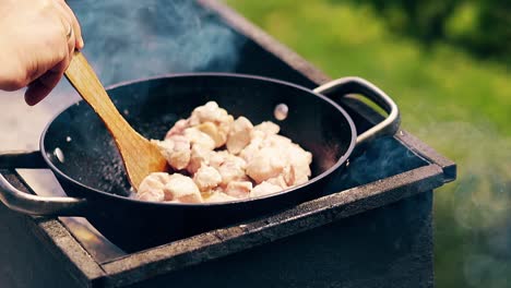 close-up cámara lenta hombre prepara un pilaf agita la carne en un caldero sobre carbón