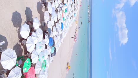 Porträtaufnahmen,-Touristen-Genießen-Den-Tropischen-Sommer-Unter-Sonnenschirmen,-Sandstrand