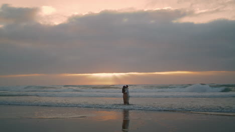 hermosa pareja girando por la mañana playa de mar. amantes románticos abrazando vertical