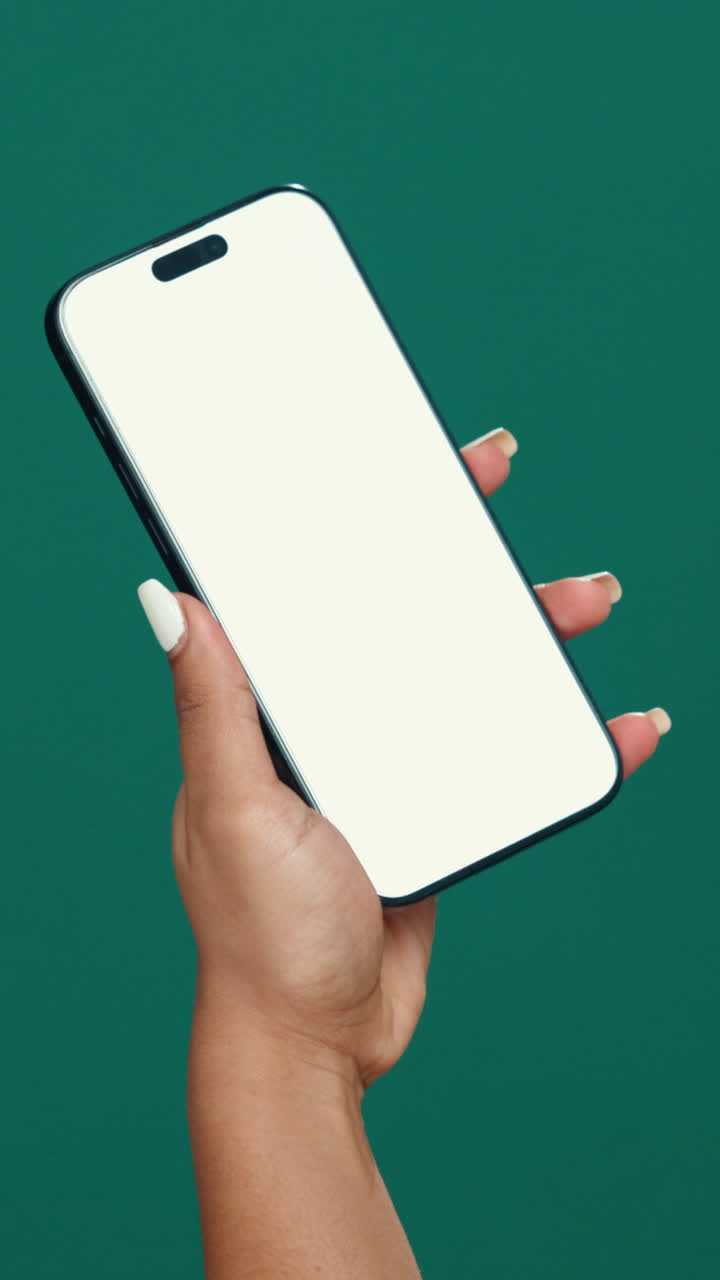 Mano che tiene uno smartphone con schermo bianco vuoto su sfondo verde