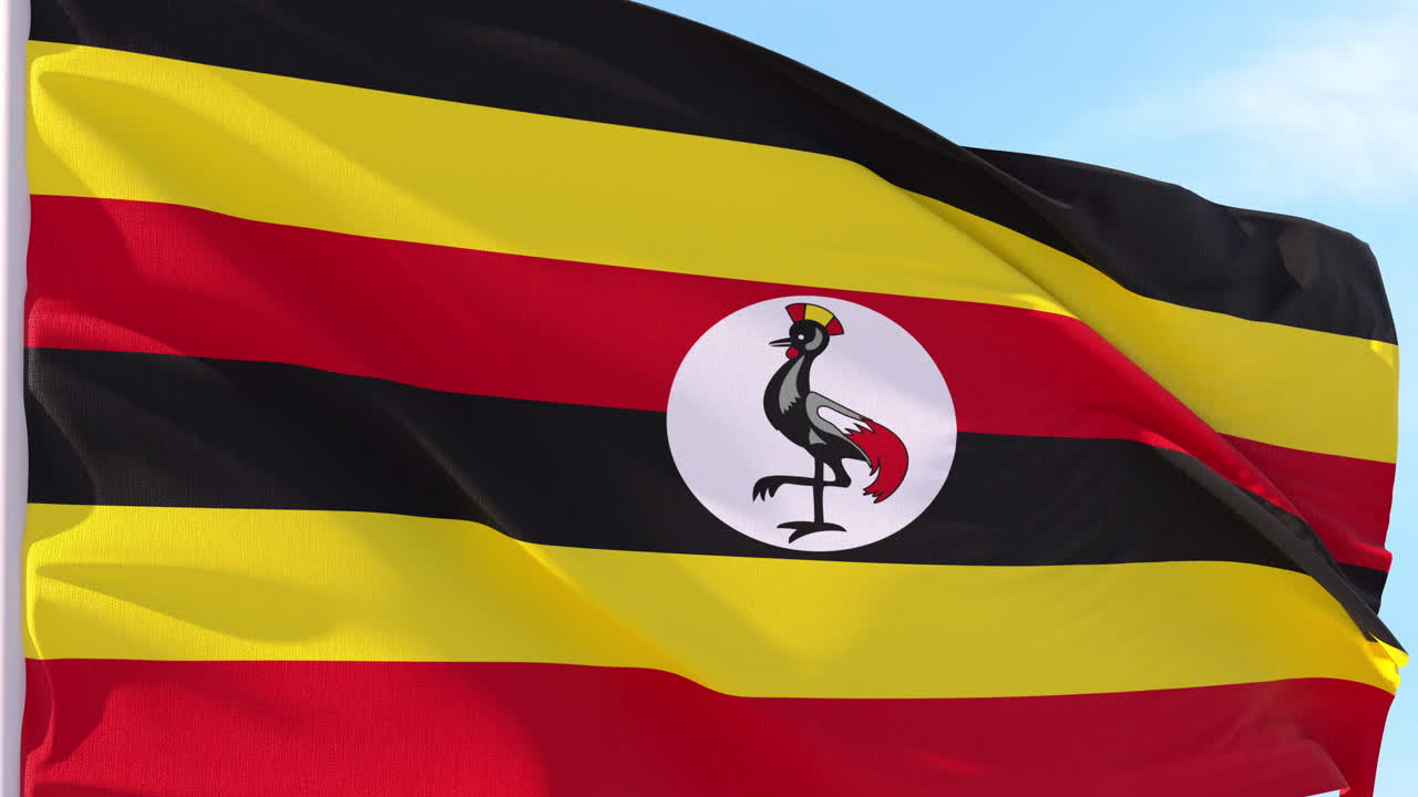 Ugandas flag vifter i vinden mod en blå himmel.