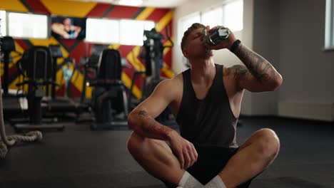 man drinking water after workout in gym