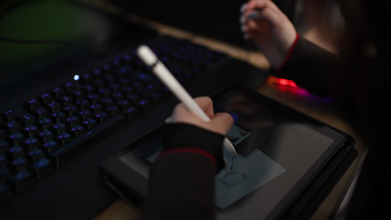 Close up of woman drawing on a tablet using stylus next to keyboard
