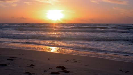 Beautiful-sunset-on-the-background-of-Baltic-sea,-sun-going-beyond-the-horizon-illuminating-water-and-clouds-in-the-sky,-calm-sea-waves,-romantic-mood,-copy-space,-wide-shot