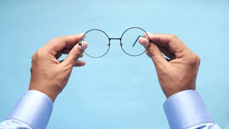 hands holding round black eyeglasses