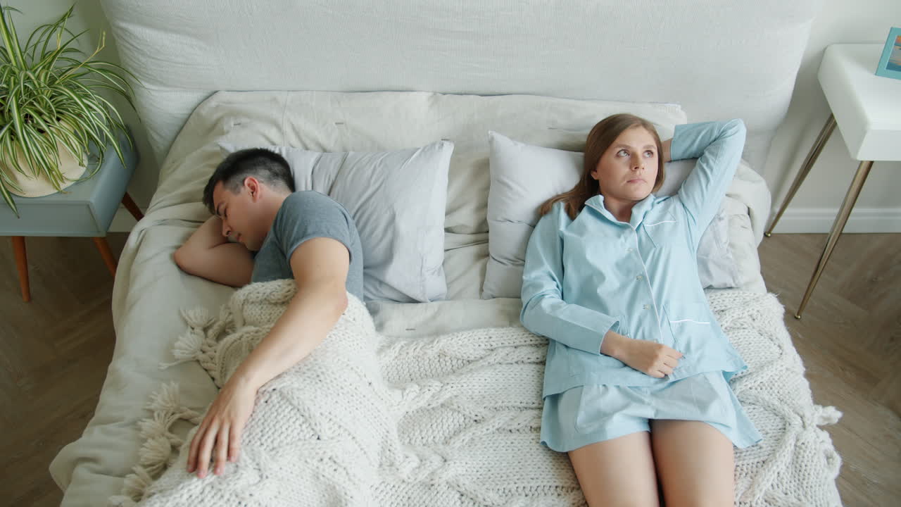 Coppia che dorme scomodamente a letto