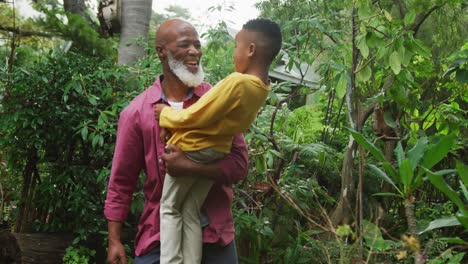 Happy-senior-african-american-man-with-his-grandson-embracing-in-garden