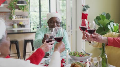 Fröhliche-Gruppe-Verschiedener-älterer-Freunde,-Die-Das-Essen-Feiern-Und-Zur-Weihnachtszeit-Mit-Wein-Anstoßen