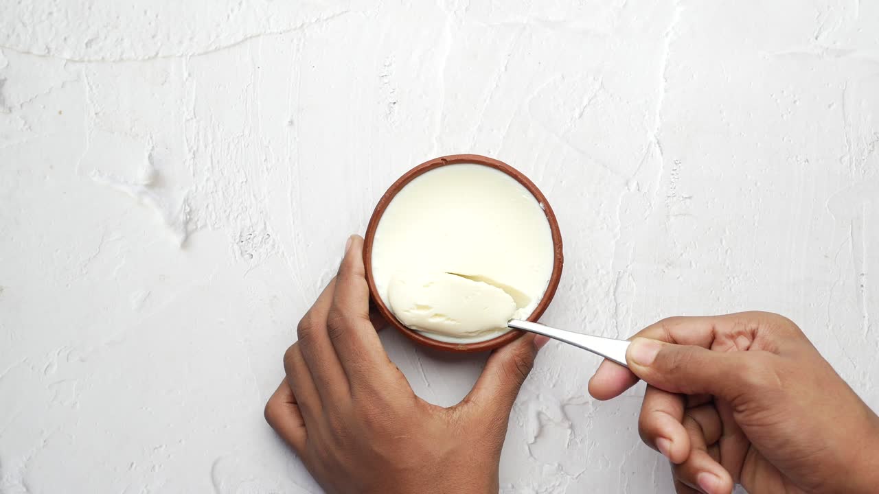 Vista dall'alto della mano dell'uomo che mangia yogurt fresco da una ciotola