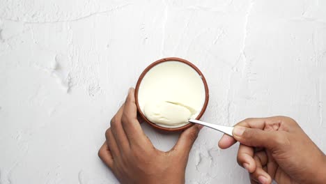 vista superior de la mano del hombre comiendo yogur fresco de un tazón
