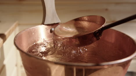 fresh water scooped up with copper ladle from copper sauna bucket, slomo