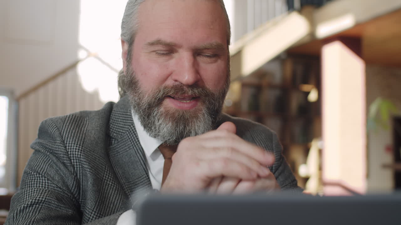 Senior Businessman Web Conferencing on Laptop in Restaurant