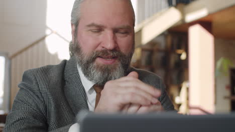 hombre de negocios sénior haciendo conferencias web en una computadora portátil en un restaurante