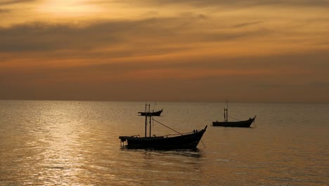 two fishing boats float peacefully on a shimmering golden sea under a vibrant sunset sky.