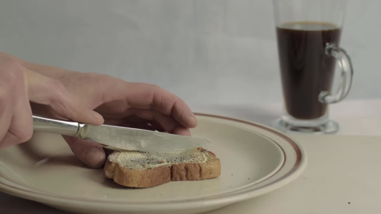 Hand cutting slice of buttered toast wide shot
