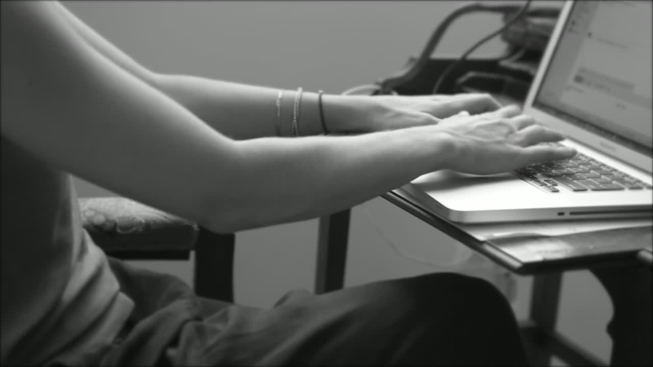 black and white video of a woman typing on a laptop keyboard whilst working her day job